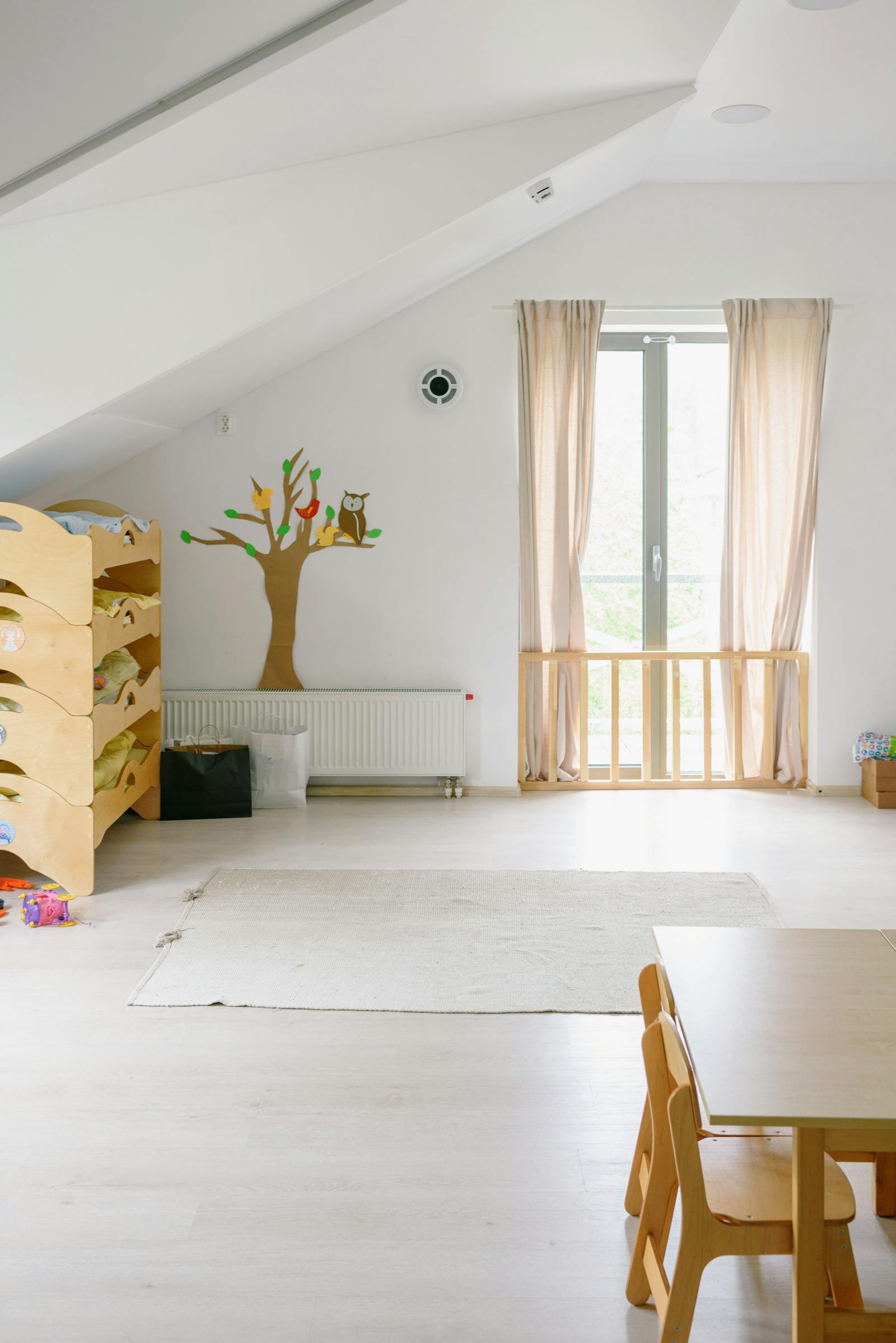 A bright, organised playroom with low open shelving, a soft floor mat, and modular seating in muted tones